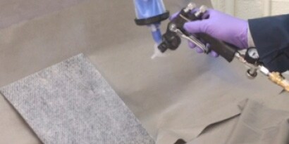 Flüssiger Klebstoff beim Sprühauftrag auf Gewebe mit einem Applikator
