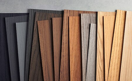 Bild von 3M DINOC Holzmaserungsmustern, geordnet von Schwarz bis zu hellen Holztönen.

