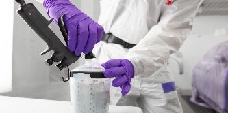 Lackierer installiert eine Düse auf einem Becher mit Lack
