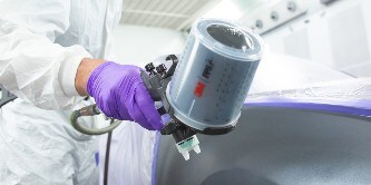 Ein Lackierer lackiert eine Auto-Oberfläche mit der 3M Hochleistungslackierpistole
