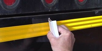 Person, die Konturband an einem LKW anbringt
