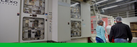 Arbeiter gehen an einer Flexodruckmaschine vorbei
