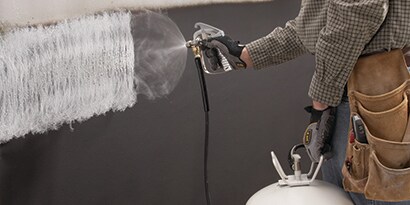 Ein Sprühklebstoff beim Auftrag auf eine große Fläche

