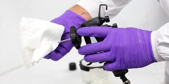 Lackierer reinigt eine Düse mit einem weißen Reinigungstuch
