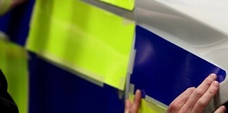 Person, die eine reflektierende Folie an einem Polizeiauto anbringt
