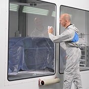 Mann reinigt ein Fenster mit einem weißen Reinigungstuch