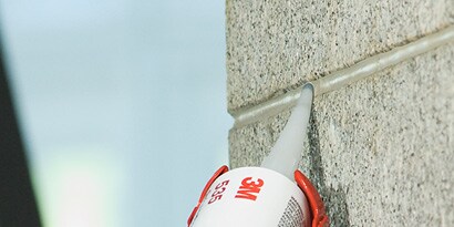 Dichtstoff beim Auftrag auf die Fuge in einer Betonwand
