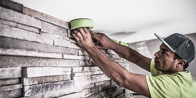 Professioneller Maler bringt 3M Abdeckband oben an einer Wand an
