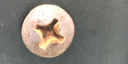 Lochfraß, Rost und galvanische Korrosion auf einem Metallschraubenkopf
