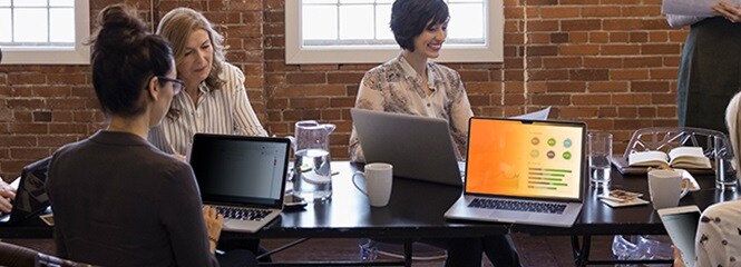 Personen, die am Tisch über Laptop-Bildschirme zusammenarbeiten
