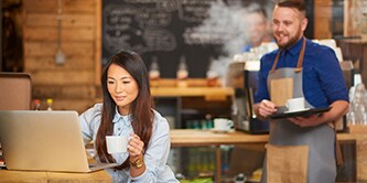 Eine Frau sitzt in einem Café und arbeitet an ihrem Laptop
