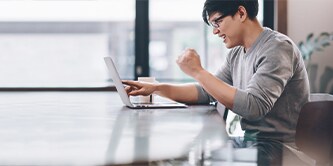 Ein Mann sitzt in einem Raum und arbeitet an einem Laptop
