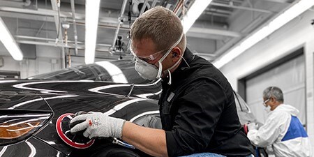 Bild zeigt einen Mann, der hochwertige Schleifmittel und Werkzeuge an einem Auto verwendet, um hervorragende Ergebnisse zu erzielen.
