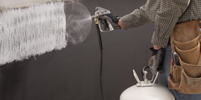 Person, die mit einem Applikator Klebstoff aufsprüht
