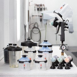 Komponenten eines 3M Hochleistungslackierpistolen-Kits wie Düsen, Adapter, Becher, Deckel
